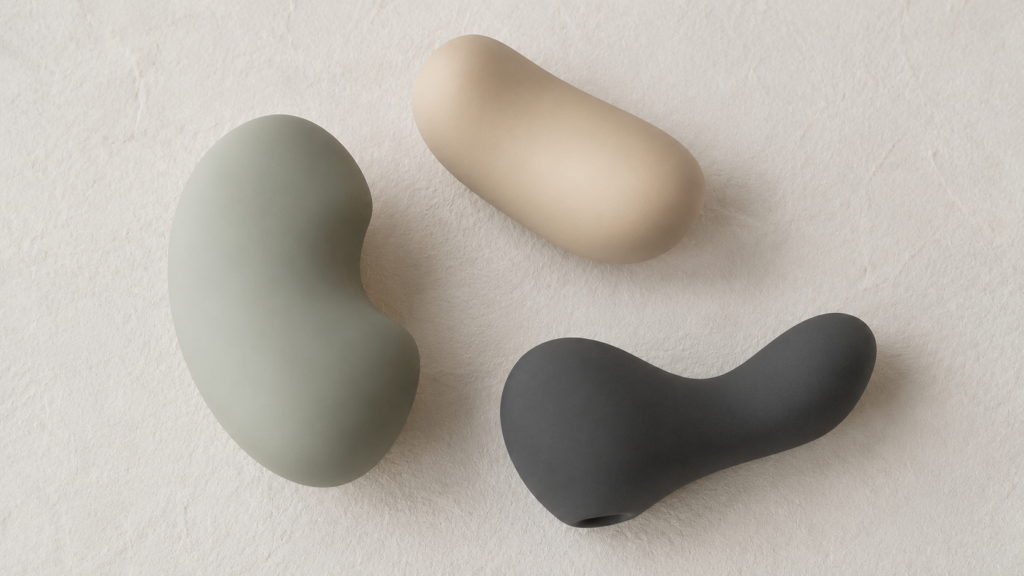Three softly shaped vibrators in sage green, sand and charcoal, illustrating how to choose a first vibrator