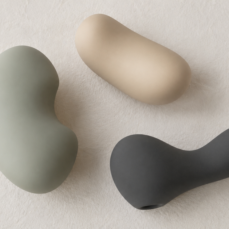 Three softly shaped vibrators in sage green, sand and charcoal, illustrating how to choose a first vibrator