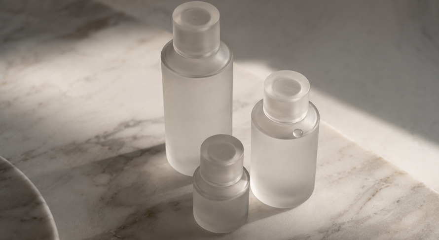 Frosted glass lubricant bottles on marble, illustrating a guide to which lubricant works with which toy material