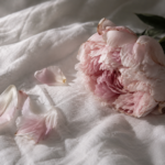 A pink peony and fallen petals resting on white linen, illustrating a guide to the causes of painful sex